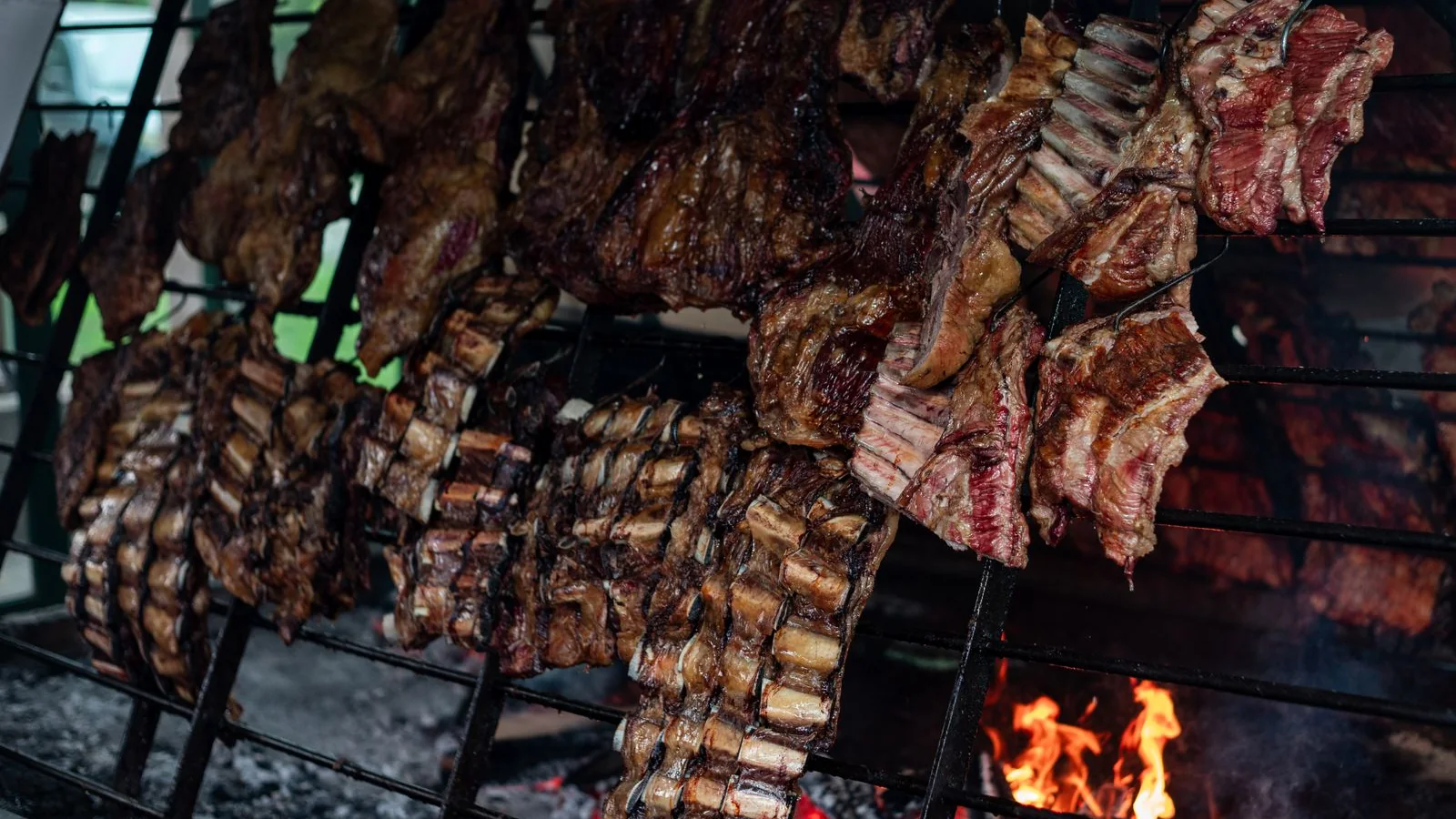 Beef ribs and cuts grilling over open coals on an Argentine parrilla (representative photograph, not La Ventana's own kitchen)